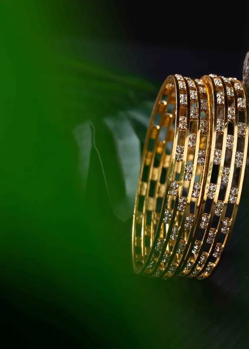 Stacked gold bangles with crystal embellishments in a multi-layered design, modern new top jewelry for festive wear